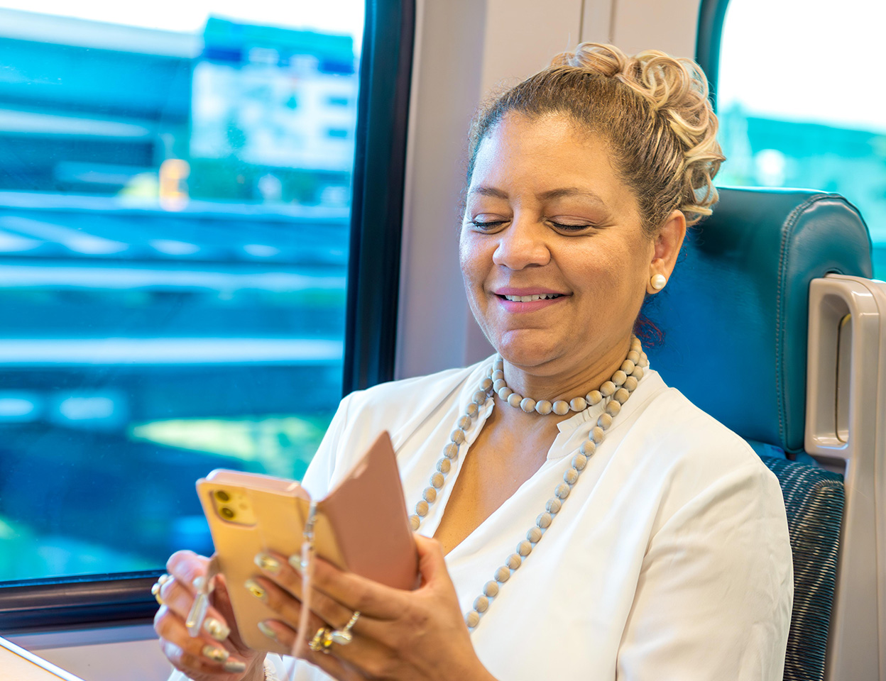 Woman riding SunRail looking at her phone.