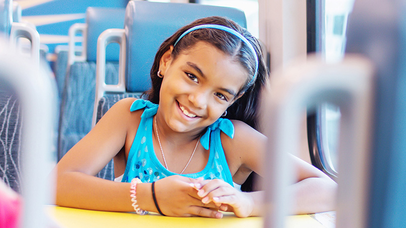 Landing page image - child passenger aboard SunRail train, sitting in a seat with arms on table.