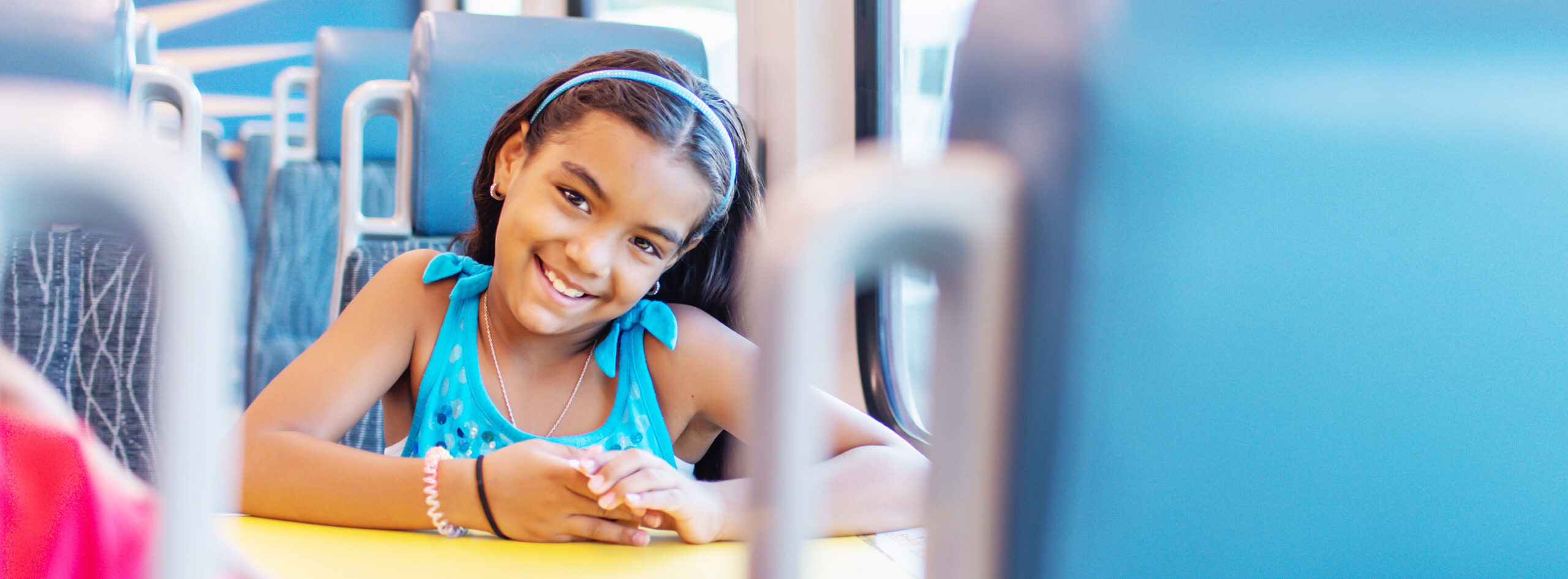 Masthead image - child passenger aboard SunRail train, sitting in a seat with arms on table.