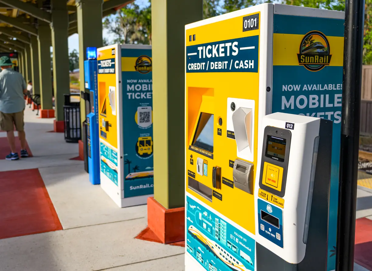 Two men exiting the Sanford Trolley. SunRail ticket vending machines and ticket validator on the station platform.