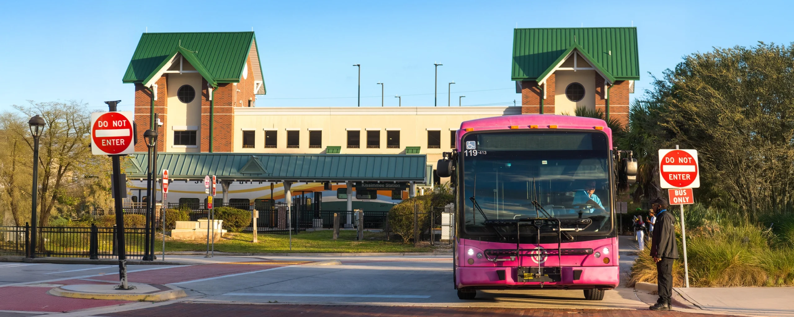 Masthead image - Sanford Trolley parked at the Sanford Station. Exterior shot of SunRail Kissimmee/Amtrak, showing LYNX bus leaving station.